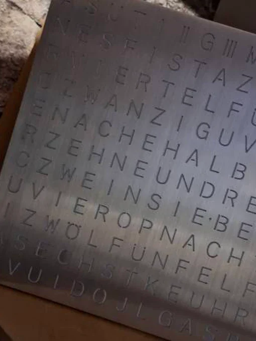 Nahaufnahme der gebürsteten Metalloberfläche einer Wortuhr